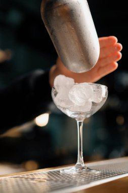 Profesyonel barmen buz küplerini bir kepçeyle soğuk kokteyllere doldurur. Yaz tatilini barda eğlenceli kılar.