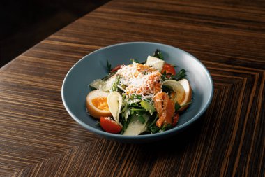 İştah açıcı taze somonlu salata restoranın sağlıklı vejetaryen yemeklerinde masada.