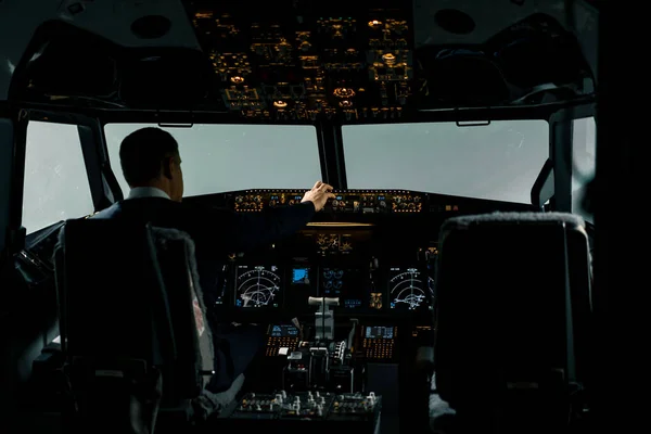 Commercial aircraft pilot adjusts aircraft flight parameters during high altitude flight View from inside cabin