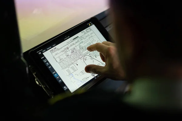 パイロットは手にタブレットを持ち飛行経路を見て飛行機の着陸場所を選択します — ストック写真