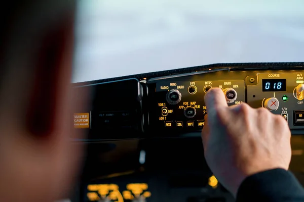 飞行员按控制面板上的动力按钮控制驾驶舱挡风玻璃前面的飞机 — 图库照片
