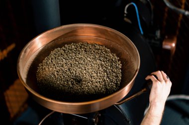 Kahve kızartma işlemi işadamı çiğ kahve çekirdeklerini bir fabrikadaki modern kızartma makinesine döküyor.