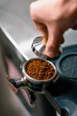 Kahve dükkanındaki profesyonel bir barista taze kahve çekirdeklerini doldurarak kahve hazırlar.