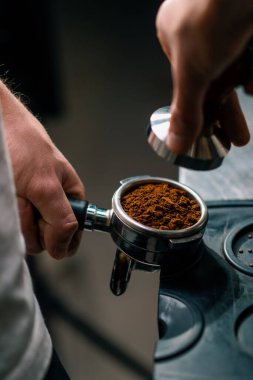 Kahve dükkanındaki profesyonel bir barista taze kahve çekirdeklerini doldurarak kahve hazırlar.