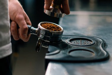 Kahve dükkanındaki profesyonel bir barista taze kahve çekirdeklerini doldurarak kahve hazırlar.
