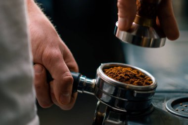 Kahve dükkanındaki profesyonel bir barista taze kahve çekirdeklerini doldurarak kahve hazırlar.