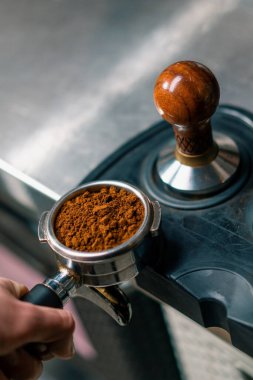 Kahve dükkanındaki profesyonel bir barista taze kahve çekirdeklerini doldurarak kahve hazırlar.