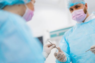 Steril eldivenli bir hemşire hastanede ameliyat sırasında cerraha cerrahi aletler veriyor.