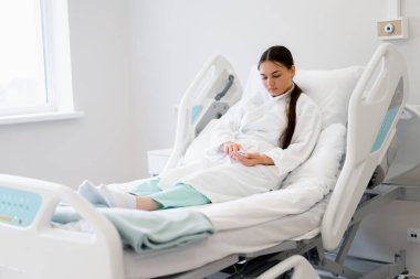 Genç hasta kız acil çağrı düğmesine basıyor ve klinikteki hastane koğuşunda hemşire yardımı istiyor.