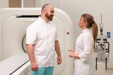 Gülümseyen ve tatmin olan doktor üniforması manyetik rezonans görüntüleme makinesi görüntüleme konsepti üzerinde tartışır.
