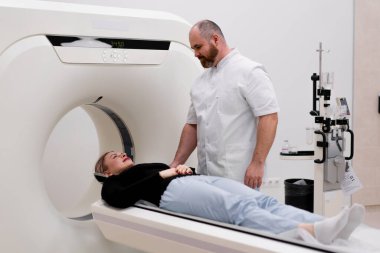 Bir klinikte bir radyoloji uzmanı bilgisayar tomografisi prosedürü uygular ve hasta üzerinde kafa muayenesi yapılır.