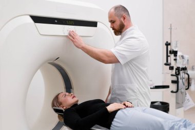 Bir klinikte bir radyoloji uzmanı bilgisayar tomografisi prosedürü uygular ve hasta üzerinde kafa muayenesi yapılır.