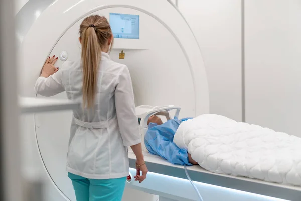 医疗诊所的专业放射学家会监察正在接受磁共振显像程序的病人 — 图库照片