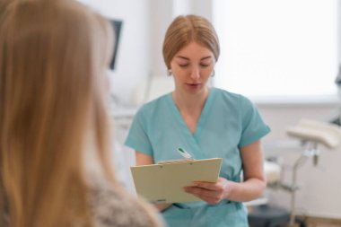 Jinekolog, jinekoloji ofisindeki modern bir klinikte tıbbi danışma sırasında bir hastayla konuşur.