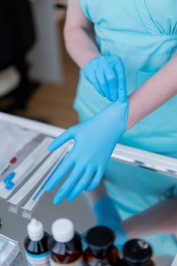Jinekolog lastik eldiven takıyor ve jinekoloji kliniğindeki hastayı yakından muayene etmeye hazırlanıyor.