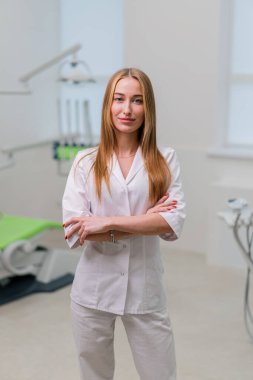 Ameliyattan önce dişçi muayenehanesinde duran güzel gülümseyen genç dişçinin portresi.