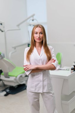 Ameliyattan önce dişçi muayenehanesinde duran güzel gülümseyen genç dişçinin portresi.