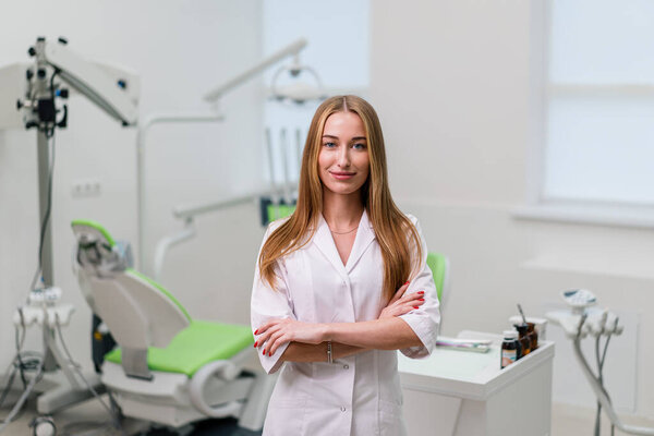 portrait of beautiful young smiling doctor dentist standing in the dental office before the procedure
