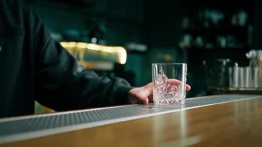 Barmenin bardağa kristal buz koyarken müşteriler için alkollü kokteyl hazırlamasını kapat.
