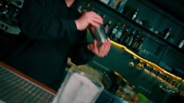 Barda kokteyl hazırlama süreci A barmeninin alkollü kokteyl malzemelerini karıştırarak karıştırması.