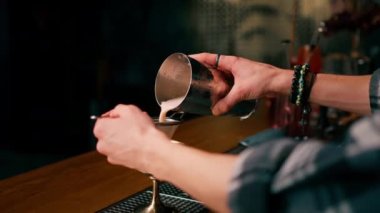 Barmen, bitmiş kokteyli bir bardağa dolduruyor. Titreştiriciden, alkol süzgecinden.