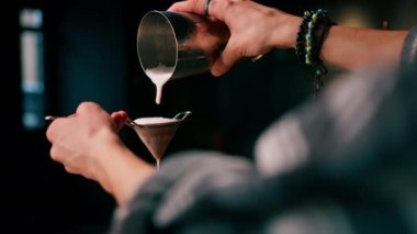 Barmen, bitmiş kokteyli bir bardağa dolduruyor. Titreştiriciden, alkol süzgecinden.