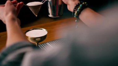 Barmen, bitmiş kokteyli bir bardağa dolduruyor. Titreştiriciden, alkol süzgecinden.