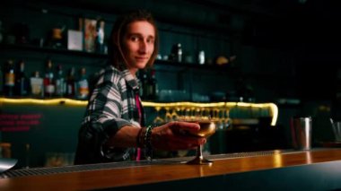 Barmen müşteriye yeni hazırlanmış ahududu sütlü kokteylinden verir.