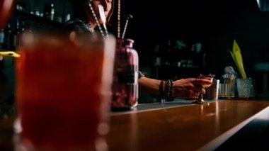 Barmen müşteriye bardan yeni hazırlanmış lezzetli bir kokteyl verir.