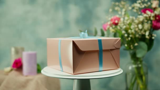 Pakowane Pyszne Ciasto Pudełku Kokardą Obraca Się Stoisku Tle Kwiatów — Wideo stockowe