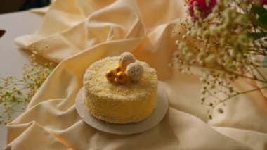 Çiçeklerin arka planında hindistan cevizi talaşı şekerleriyle süslenmiş lezzetli taze kremalı kek.