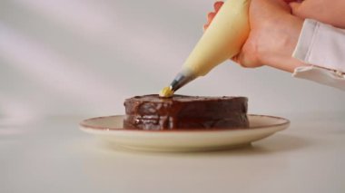 Lezzetli taze çikolatalı Sacher veya Prag keki beyaz arka planda pastadan yapılmış kremayla süslenmiş.