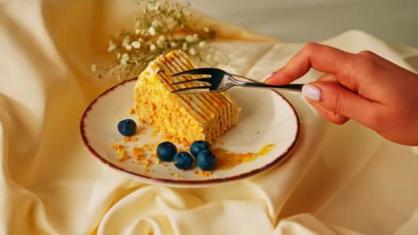 叉子切一片美味的蜂蜜蛋糕 盘中撒满蜂蜜 背景是米黄色的浆果 — 图库视频影像