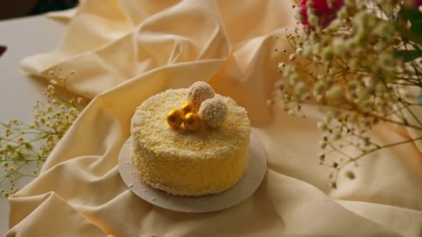 美味的新鲜奶油海绵蛋糕 用椰子碎制成的金黄色糖果装饰 以花朵为背景 — 图库视频影像