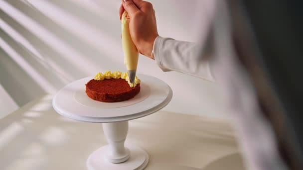 美味的新准备的蛋糕 红色天鹅绒 在白色的背景上 蛋糕装饰着奶油糖霜从糕点袋 — 图库视频影像