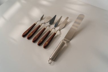 Masadaki beyaz arka plandaki pastalar için farklı spatulalar pişirme aletleri.