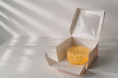 Pastanenin tatlı tatlı bayramında beyaz arka planda hediye kutusunda taze yapılmış ballı kek.