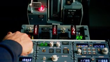 Kaptan, uçuş simülatörünün motorunu çalıştırmak için kontrol panelindeki düğmelere basar.