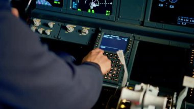 Pilot uçuş simülatörü sırasında uçağı kontrol etmek için kontrol panelindeki güç düğmelerine basar.