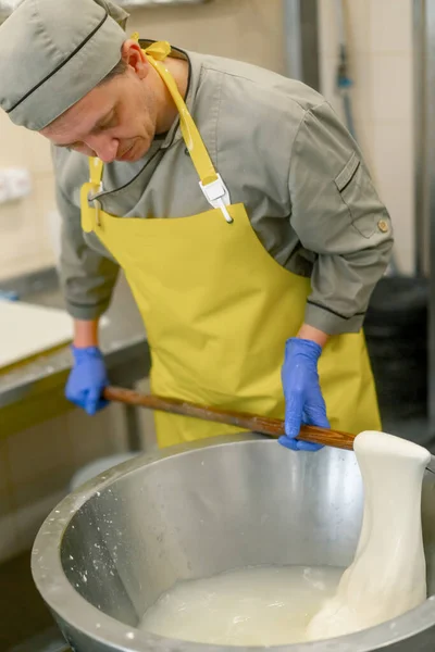 乳酪的生产奶酪制造者从高温的金属桶中取出白毛霉 — 图库照片