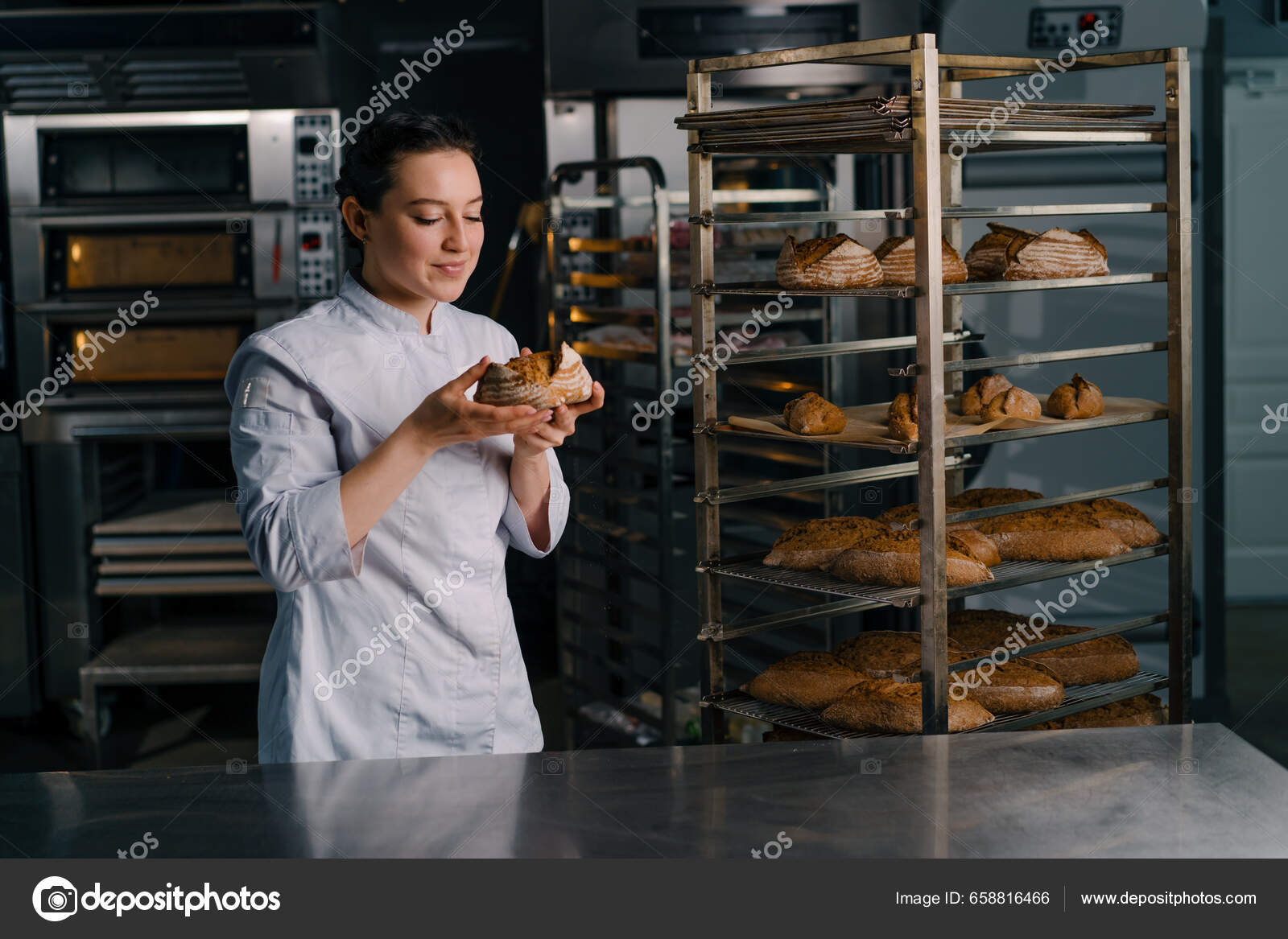 Baker taking out freshly baked bread from the oven of a bakery stock photo