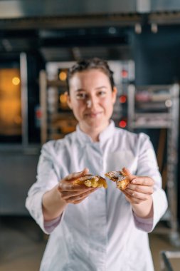 Gülümseyen güzel kadın fırıncı taze pişmiş sıcak kokulu çörekleri yırtıyor hamur kontrol ederken çörek fırını üretimini gösteriyor