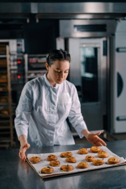 Çekici fırıncı masaya yeni pişmiş sıcak kokulu çöreklerle birlikte bir fırın örtüsü koyar.