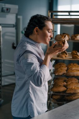 Çekici kadın fırıncı raftan taze kokulu ekmek alır kaliteli fırın profesyonel pişirme kontrol eder.