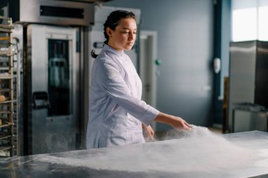 Profesyonel aşçı, ekmek hamurunu pişirmeden önce un yapmak için masaya un döker.