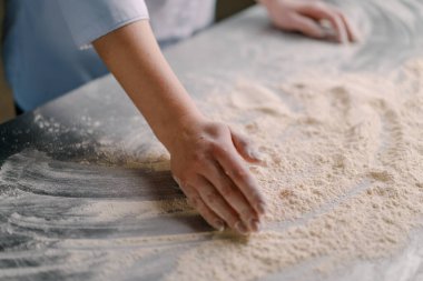 Profesyonel bir şef masaya un döker. Profesyonel bir mutfakta fırında ekmek pişirmeden önce karıştırır.