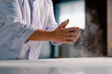 Deneyimli bir şef, ekmek yapmadan önce ellerine un sürer ve profesyonel mutfakta hamur işleri hazırlar.