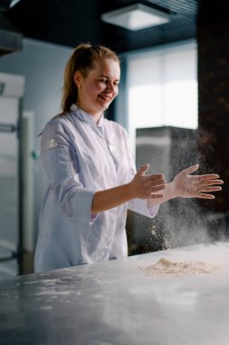 Deneyimli bir şef, ekmek yapmadan önce ellerine un sürer ve profesyonel mutfakta hamur işleri hazırlar.