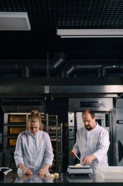İki fırıncı hamur işini pişirmeden önce şekillendirir, keser ve profesyonel pasta imalatına sunar.