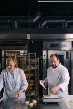 İki fırıncı hamur işini pişirmeden önce şekillendirir, keser ve profesyonel pasta imalatına sunar.